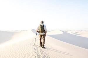 Man walking alone in a vast desert landscape photo