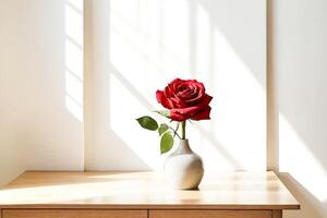 Single Red Rose in a White Vase on a Wooden Table with Sunlight Streaming Through Window photo