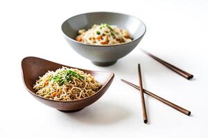 Closeup of noodles in a bowl with chopsticks on a white surface photo