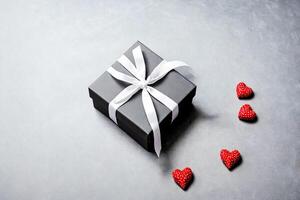 Black gift box with white ribbon and red hearts on gray background photo