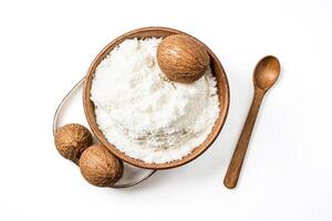 Coconut flakes in a wooden bowl with coconuts and a wooden spoon on a white background photo