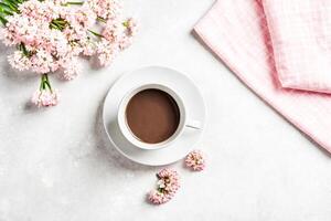 Flat lay composition with a cup of coffee and pink flowers photo