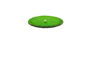 Golf ball on a tee on a green patch of grass isolated on white background photo