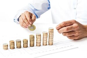 Hand Adding Coin to Stack of Coins on Graph photo
