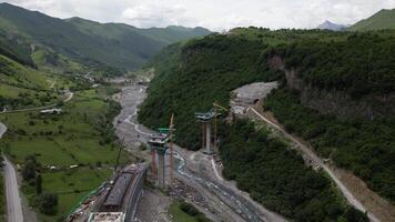 Kazbegi, Georgia - 7th july, 2024 - aerial view cranes and bridge foundation pillars on construction site of new highway road project built by chinese builders.Avalanche bypass tunnel.Tbillisi - Lars video