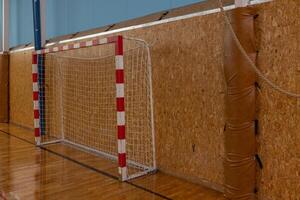 Indoor Sports Goalpost in Gymnasium with Wooden Wall, Red and White Net for Team Practices. photo