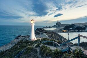 View of Castlepoint Lighthouse with beam on Wairarapa coast in the evening at New Zealand photo