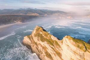 Sunrise shining over Wharariki beach and archway islands on Tasman sea at Cape Farewell, New Zealand photo