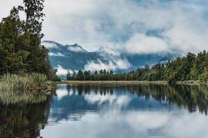 Lake Matheson glacier lake with mountain range and foggy reflection at New Zealand photo