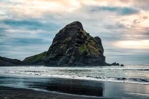 Rocky mountain on Piha beach in the evening at West coast of Auckland photo