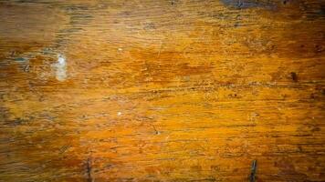 Close-up of wood surface texture with very clear wood grain, brown tones and darker streaks indicating natural pattern. There are small scratches and stains throughout the surface photo