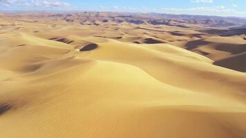 A vast desert with rolling sand dunes. Bright, natural lighting to highlight the textures and patterns. video