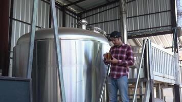 A Man tasting craft beer In the back is a large brewery with the concept of making your own craft beer. video