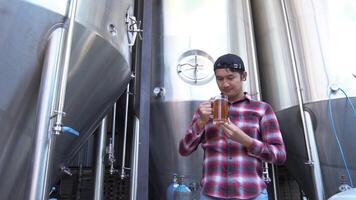 A Man tasting craft beer In the back is a large brewery with the concept of making your own craft beer. video