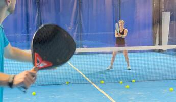 Empowering padel tennis training as a coach skillfully instructs a young woman on the court, fostering skill development and a positive learning environment photo