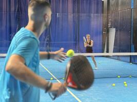 Empowering padel tennis training as a coach skillfully instructs a young woman on the court, fostering skill development and a positive learning environment photo