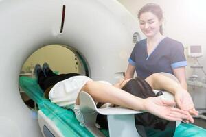 Radiologic technician and Patient being scanned and diagnosed on computed tomography scanner in hospital photo