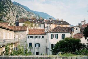 Ancient stone houses with shutters on the windows and red roofs at the foot of the mountains. Kotor, Montenegro photo