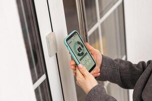 Smiling woman setting home security system with help of mobile application. photo
