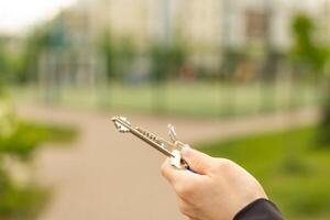 Close up of hands of young woman holding house keys of her new house. Woman hand holding housekey shaped keychain. Girl buying new home for her family and showing key with copy space. photo