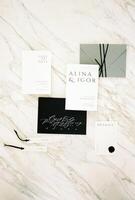 Wedding invitations with envelopes and name tags lie on a white marble table photo