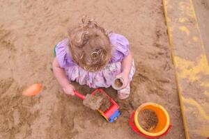 Child playing in the sandbox in the playground in the courtyard of a house photo