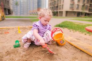 Child playing in the sandbox in the playground in the courtyard of a house photo