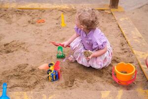 Child playing in the sandbox in the playground in the courtyard of a house photo