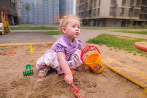 Child playing in the sandbox in the playground in the courtyard of a house photo