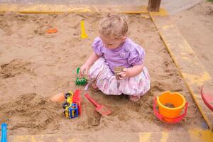 Child playing in the sandbox in the playground in the courtyard of a house photo