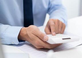 Businessman Saving money analyzing investment charts and pressing calculator buttons over documents. Accounting Concept photo