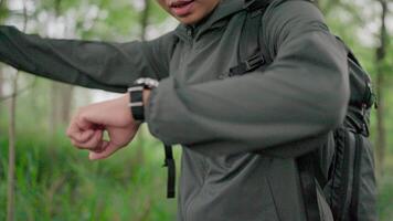 The hiking man was tired and worried about the route, using a compass to choose a route. Man overcomes obstacles while hiking in a tropical forest video
