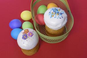 Easter cake and easter eggs in a basket on red background photo