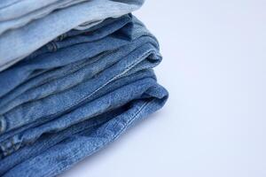 Lots of jeans pants in a stack. Denim background. photo