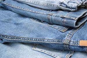 Lots of jeans pants in a stack. Denim background. photo