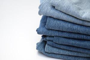 Lots of jeans pants in a stack. Denim background. photo