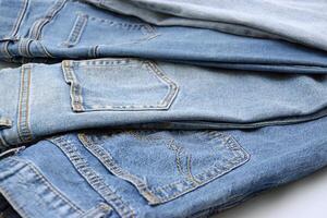 Lots of jeans pants in a stack. Denim background. photo