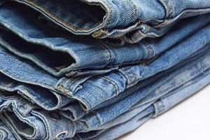 Lots of jeans pants in a stack. Denim background. photo