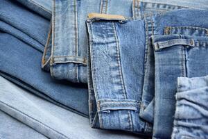 Lots of jeans pants in a stack. Denim background. photo