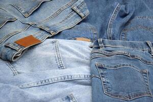 Lots of jeans pants in a stack. Denim background. photo