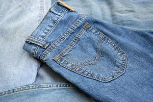 Lots of jeans pants in a stack. Denim background. photo
