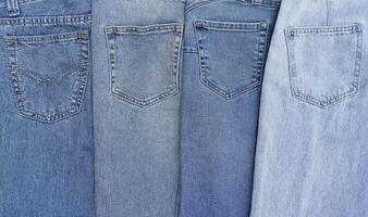 Lots of jeans pants in a stack. Denim background. photo