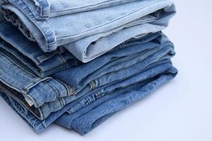 Lots of jeans pants in a stack. Denim background. photo