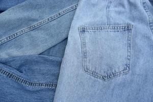 Lots of jeans pants in a stack. Denim background. photo