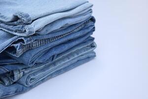 Lots of jeans pants in a stack. Denim background. photo