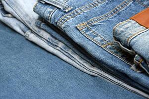 Lots of jeans pants in a stack. Denim background. photo