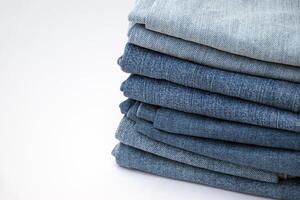 Lots of jeans pants in a stack. Denim background. photo