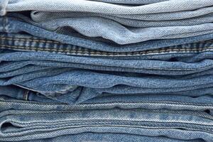 Lots of jeans pants in a stack. Denim background. photo