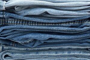 Lots of jeans pants in a stack. Denim background. photo
