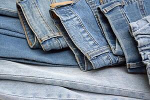 Lots of jeans pants in a stack. Denim background. photo